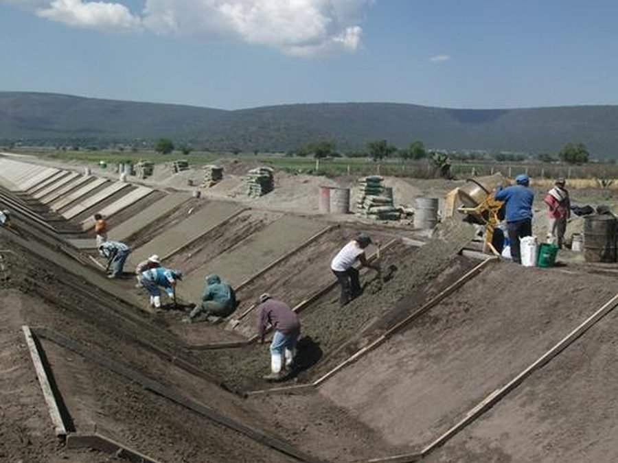 Cuadrilla revistiendo de concreto un canal de riego