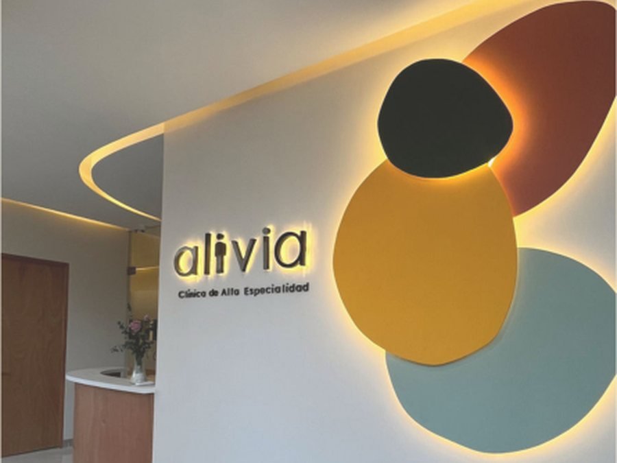 Recepción de clínica Alivia con muro de identidad iluminado